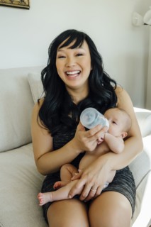 Portrait of smiling mother feeding bottle to baby daughter