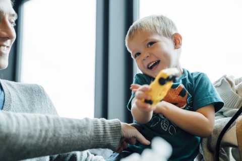 Arm of mother tickling son holding toy car