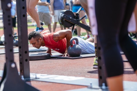 Man doing push-ups near kettlebell outdoors
