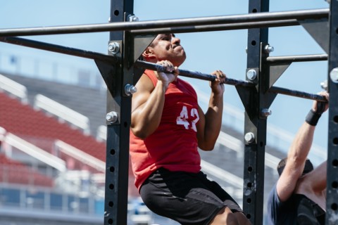 Hispanic man doing chin-ups outdoors