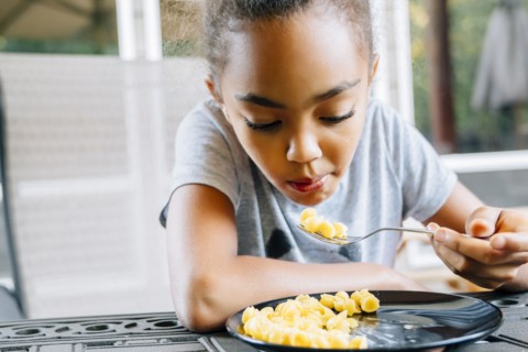 Mixed Race girl eating food with fork