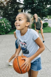 Mother and daughters playing basketball in driveway