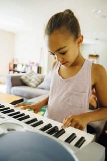Mixed Race girl playing music on keyboard