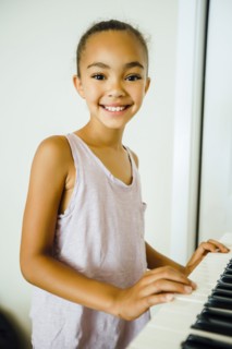 Smiling Mixed Race girl playing music on keyboard