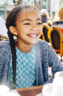 Smiling Mixed Race girl sitting at restaurant table