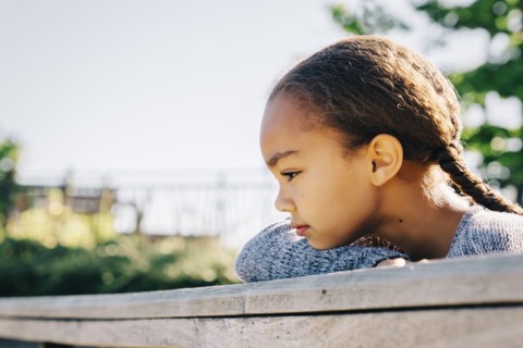 Pensive Mixed Race girl leaning on wooden railing