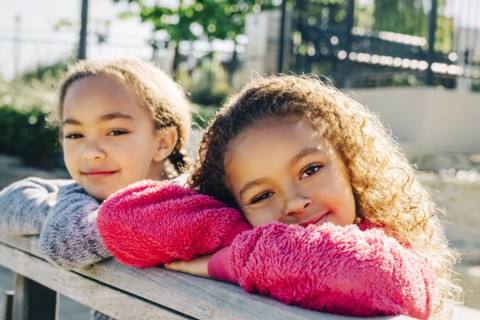 Mixed Race sisters leaning on wooden railing