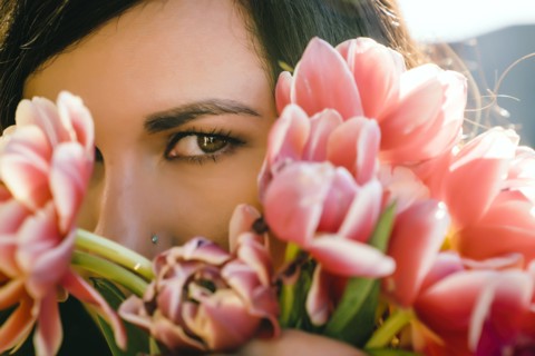 Mixed Race woman hiding face behind flowers