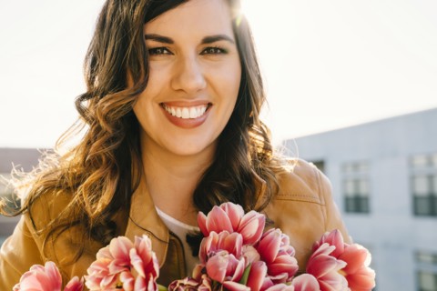 Portrait of smiling Mixed Race woman holding flowers