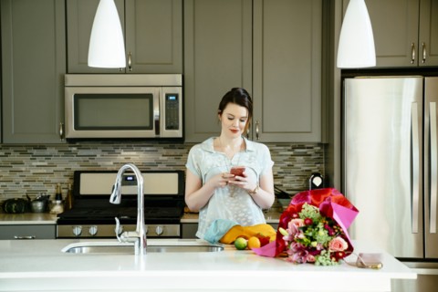 Woman texting on cell phone in domestic kitchen