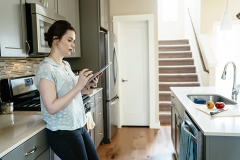 Woman using digital tablet in domestic kitchen