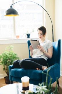Woman sitting in armchair using digital tablet