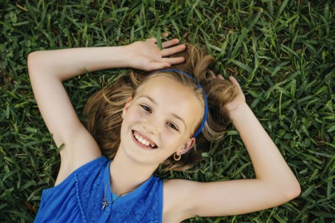 Close up portrait of smiling Caucasian girl laying on grass