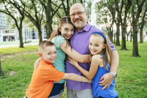 Portrait of Caucasian boy and girls hugging father in park
