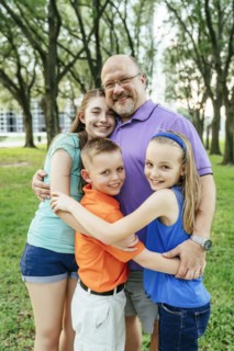 Portrait of Caucasian boy and girls hugging father in park
