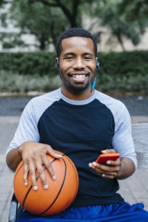Portrait of Black man listening to earbuds and holding basketball