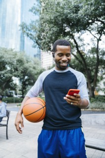Portrait of Black man listening to earbuds and holding basketball