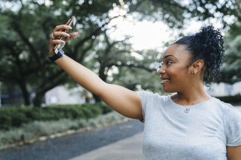 Smiling Black woman posing for cell phone selfie
