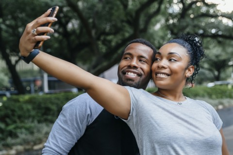 Smiling Black couple posing for cell phone selfie