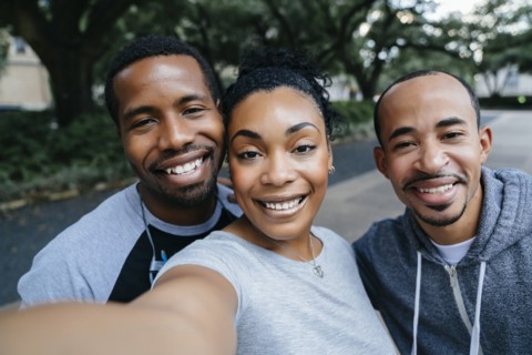 Smiling Black friends posing for cell phone selfie
