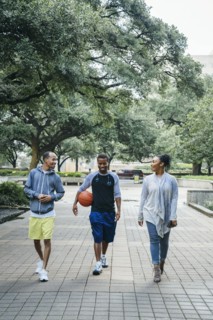 Smiling Black friends walking in park with basketball