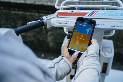 Hands of Black woman paying for bicycle rental with cell phone
