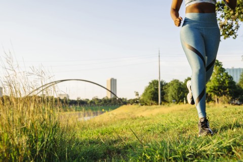 Legs of mixed race woman running in grass near waterfront