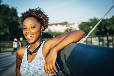 Smiling mixed race woman listening to earbuds on bridge