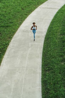 Distant mixed race woman running on path in park