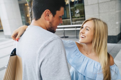 Caucasian couple hugging and carrying shopping bags