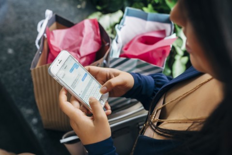 Hispanic woman with shopping bags texting on cell phone