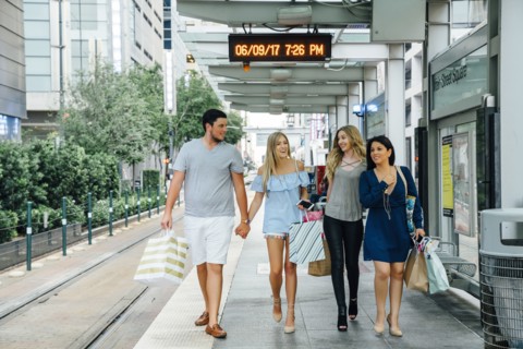 Friends walking at train station carrying shopping bags