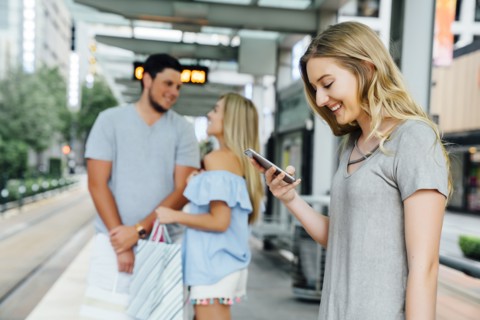 Caucasian woman at train station texting on cell phone