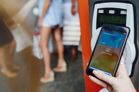 Hand of woman paying at kiosk using cell phone