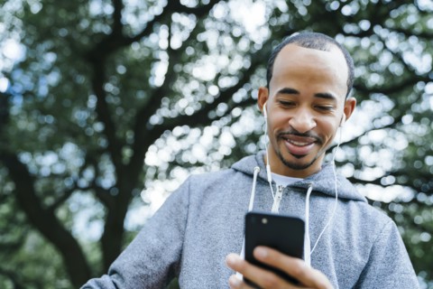 Black man listening to cell phone with earbuds