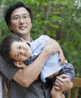 Asian father carrying son
