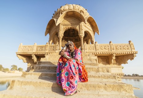 Indian woman in traditional clothes sitting near monument