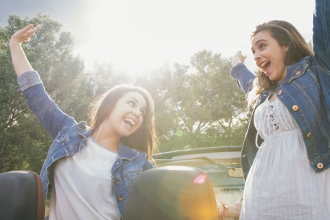 Women cheering in convertible