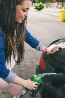 Hispanic woman fueling car in gas station