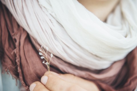 Caucasian woman holding delicate leaf near scarf