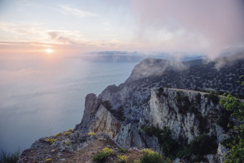 Sunrise from foggy ocean cliff