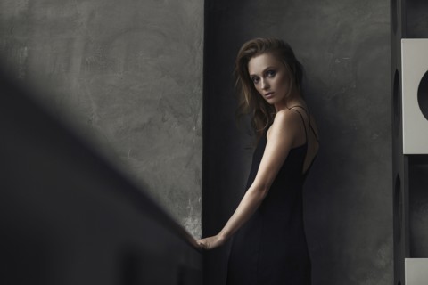 Serious Caucasian woman standing near wall