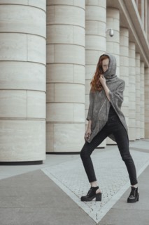 Caucasian woman hiding face behind hood near pillars