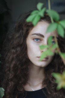 Portrait of serious Caucasian woman behind leaves