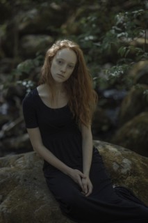Serious Caucasian woman sitting on rock