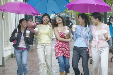 Group of women walking and laughing with umbrellas