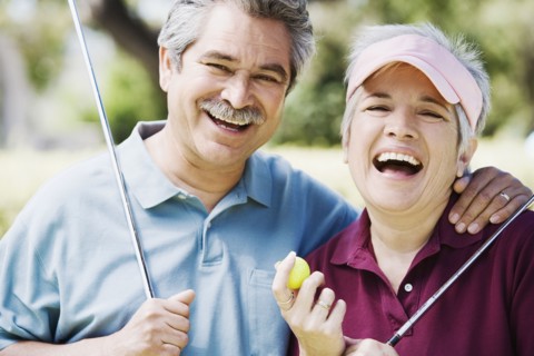 Middle-aged couple laughing with golf clubs