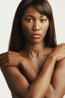 Nude African woman covering breasts