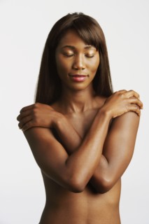 Nude African woman covering breasts