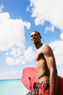 African man holding body board on beach